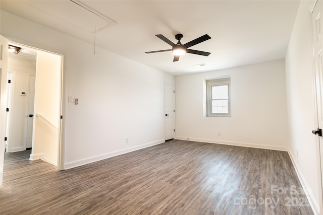 empty room with attic access, visible vents, baseboards, and wood finished floors