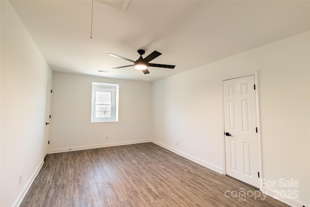 spare room with attic access, baseboards, visible vents, a ceiling fan, and wood finished floors