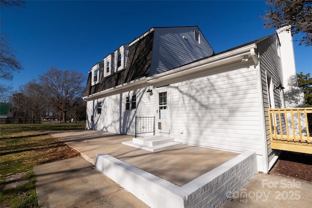 view of property exterior featuring a chimney and a gambrel roof