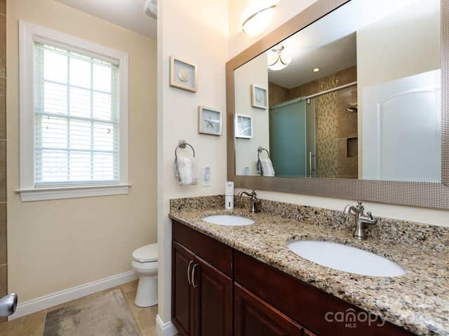 bathroom featuring a sink, a shower stall, toilet, and double vanity