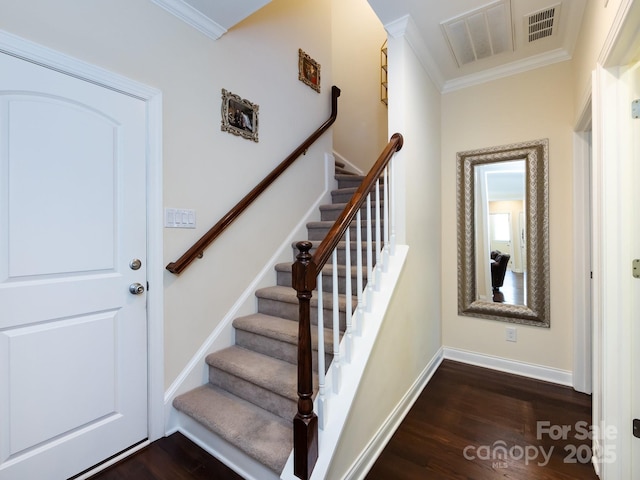 stairs with ornamental molding, visible vents, baseboards, and wood finished floors