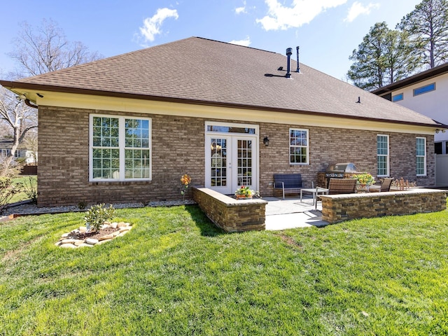 back of property with a shingled roof, a patio area, and a lawn