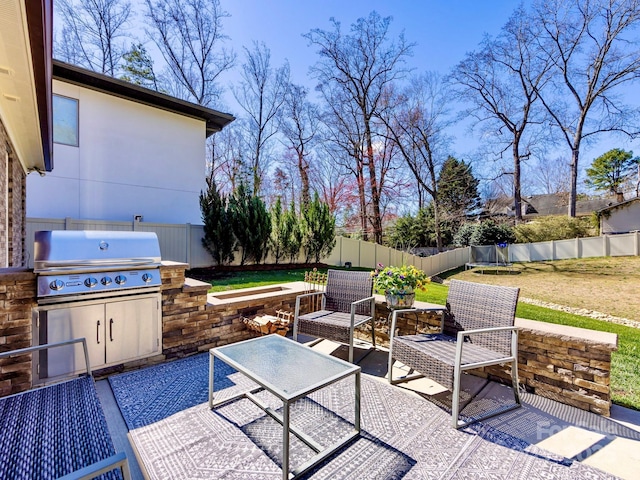 view of patio / terrace featuring a trampoline, area for grilling, a fenced backyard, and an outdoor living space