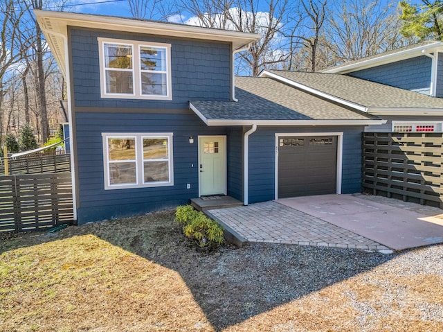 view of front facade featuring driveway, a garage, fence, and roof with shingles