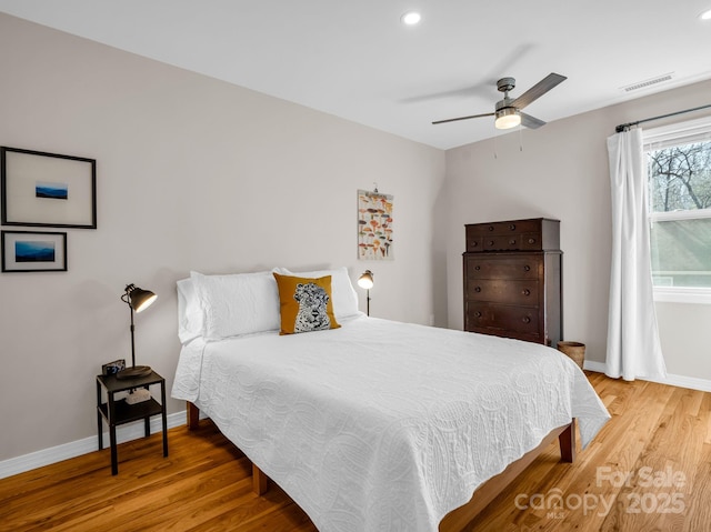 bedroom with baseboards, visible vents, and wood finished floors