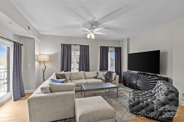 living area featuring baseboards, a ceiling fan, visible vents, and light wood-style floors