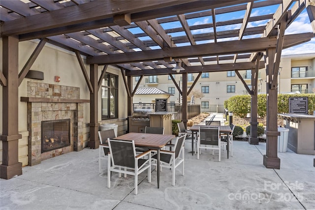 view of patio featuring outdoor dining space, an outdoor stone fireplace, area for grilling, and a pergola