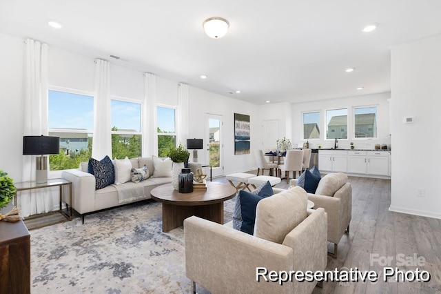 living room with baseboards, light wood finished floors, visible vents, and recessed lighting