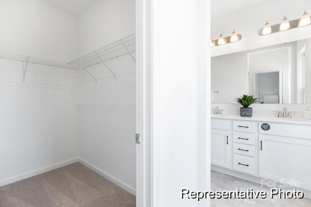 walk in closet with light colored carpet and a sink