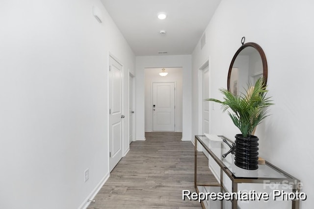 hallway with visible vents, light wood-style flooring, and baseboards