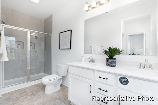 bathroom featuring a sink, a shower stall, toilet, and double vanity