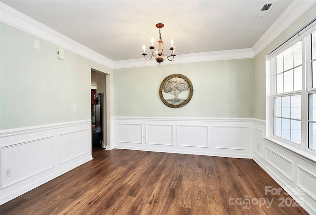 unfurnished dining area with visible vents, dark wood finished floors, wainscoting, ornamental molding, and a notable chandelier