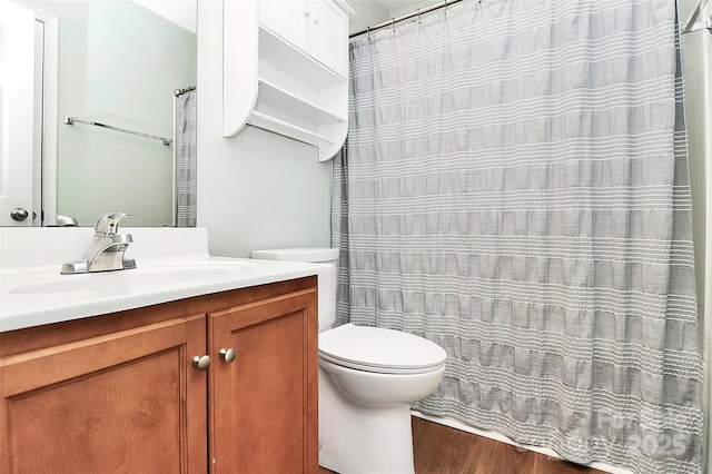 bathroom featuring toilet, wood finished floors, and vanity