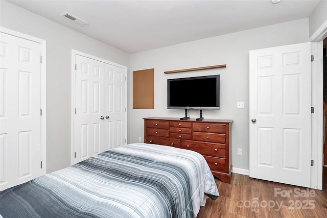 bedroom with a closet, visible vents, and wood finished floors