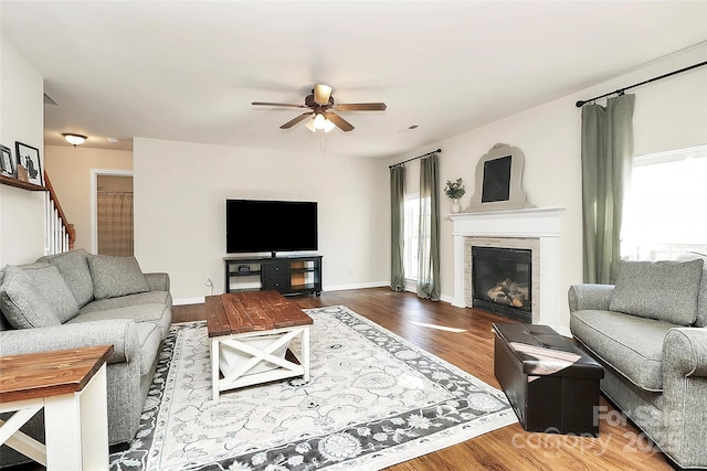 living room with plenty of natural light, wood finished floors, a ceiling fan, and baseboards