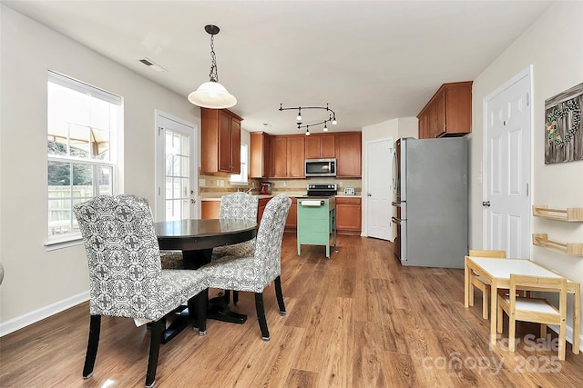 dining space with rail lighting, baseboards, visible vents, and light wood finished floors