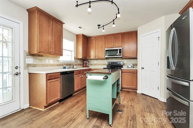 kitchen featuring a sink, brown cabinetry, stainless steel appliances, and light wood-style floors