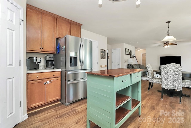 kitchen featuring brown cabinetry, light wood-type flooring, stainless steel fridge, and a kitchen island