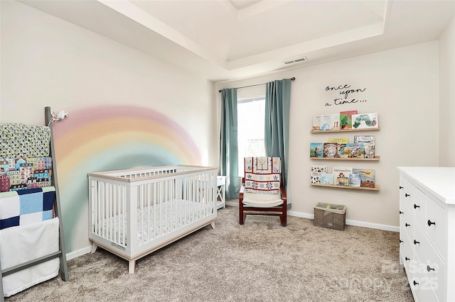 bedroom featuring a crib, visible vents, a raised ceiling, and light colored carpet