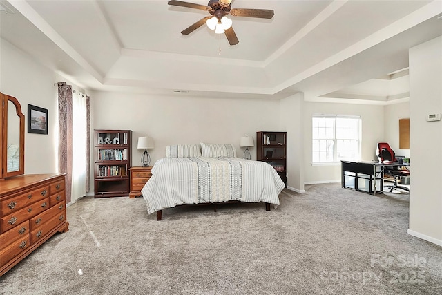 bedroom featuring a tray ceiling, carpet, a ceiling fan, and baseboards