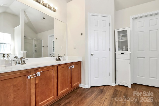 bathroom with visible vents, vaulted ceiling, a sink, and wood finished floors