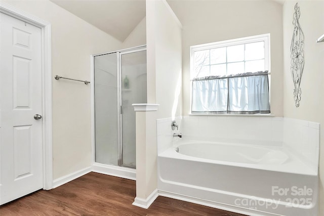 full bath with baseboards, wood finished floors, vaulted ceiling, a shower stall, and a bath