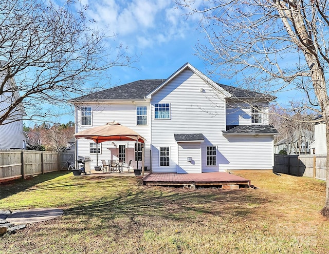 rear view of house with a deck, a gazebo, a lawn, and a fenced backyard