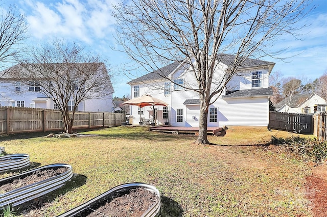 exterior space featuring a vegetable garden, a fenced backyard, a lawn, and a wooden deck