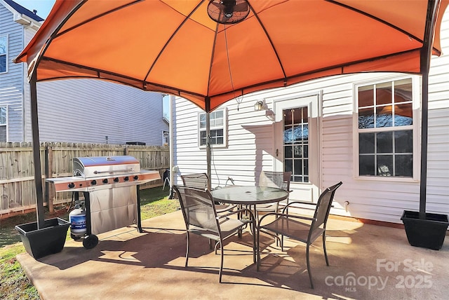 view of patio featuring outdoor dining area, fence, grilling area, and a gazebo