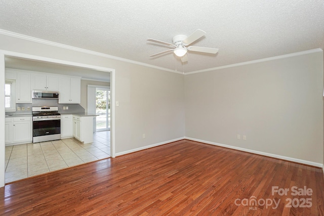 interior space featuring light wood finished floors, white cabinets, appliances with stainless steel finishes, ornamental molding, and a textured ceiling