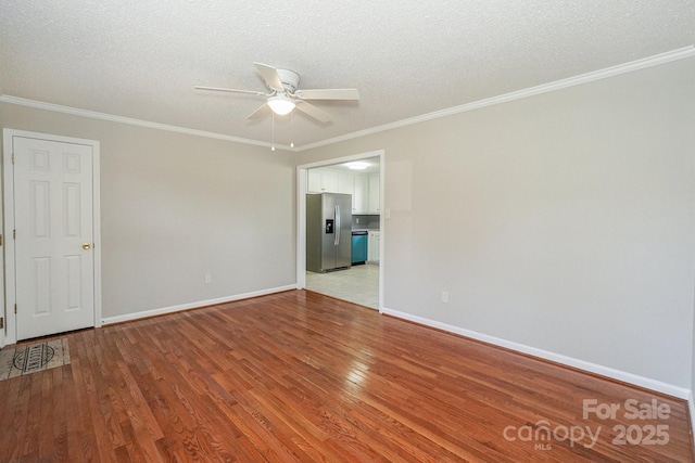 spare room with baseboards, light wood-type flooring, and crown molding