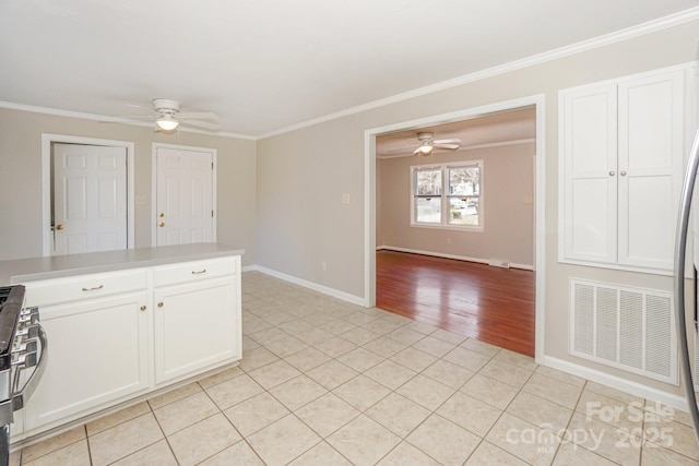 kitchen featuring light tile patterned floors, visible vents, white cabinetry, stainless steel range with gas stovetop, and crown molding