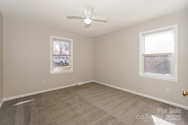 carpeted empty room with a textured ceiling, ceiling fan, visible vents, and baseboards