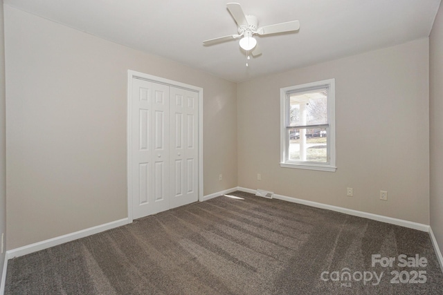 unfurnished bedroom with dark colored carpet, a closet, visible vents, and baseboards