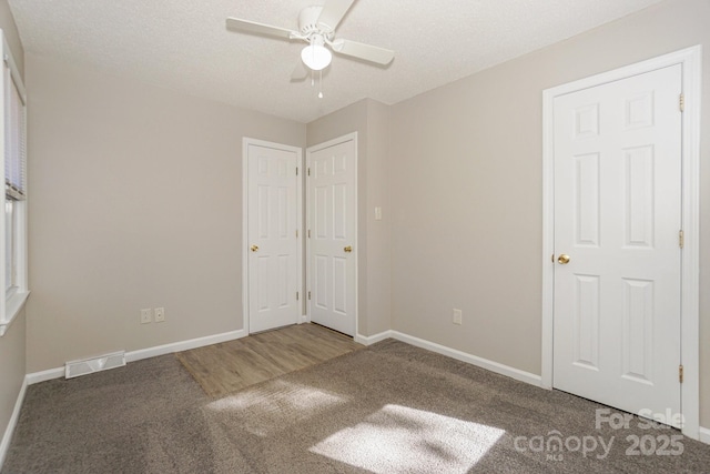 unfurnished bedroom with carpet floors, visible vents, and baseboards