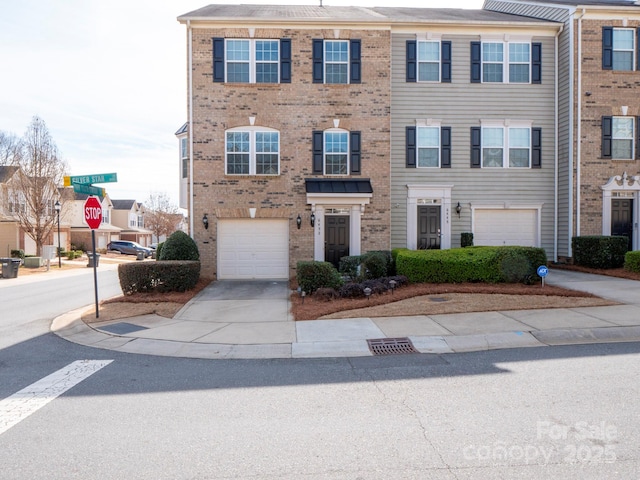 multi unit property featuring brick siding, driveway, and an attached garage