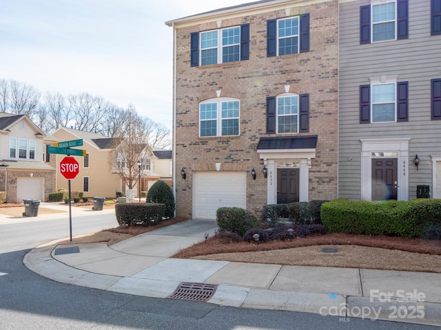 multi unit property with a garage, driveway, and brick siding