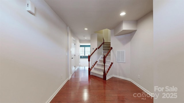 hallway featuring dark wood-type flooring, visible vents, stairway, and baseboards