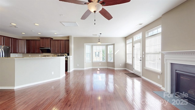 unfurnished living room featuring recessed lighting, visible vents, a fireplace with flush hearth, light wood-type flooring, and baseboards