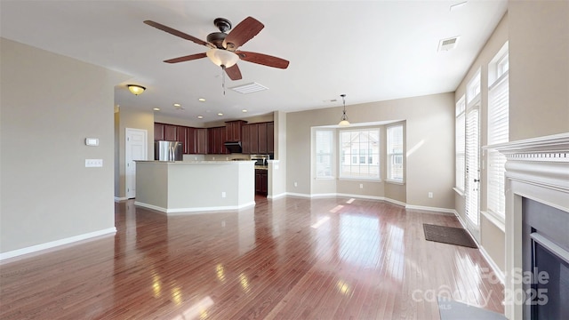 unfurnished living room with dark wood-style flooring, a fireplace with flush hearth, visible vents, and baseboards