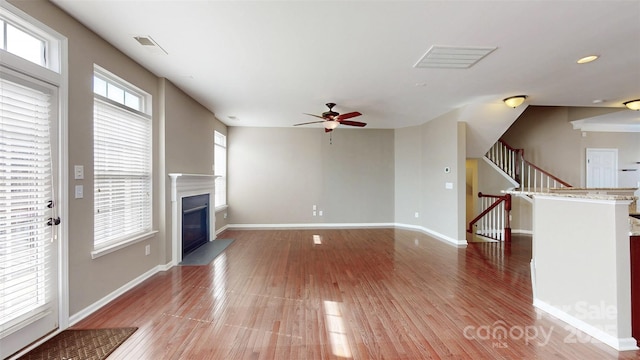 unfurnished living room featuring visible vents, a fireplace with flush hearth, light wood-style flooring, and baseboards