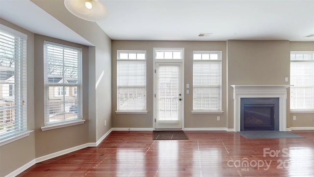 entryway featuring a fireplace with flush hearth, visible vents, baseboards, and wood finished floors