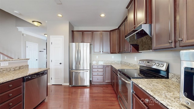 kitchen featuring appliances with stainless steel finishes, dark wood-style flooring, under cabinet range hood, and light stone countertops