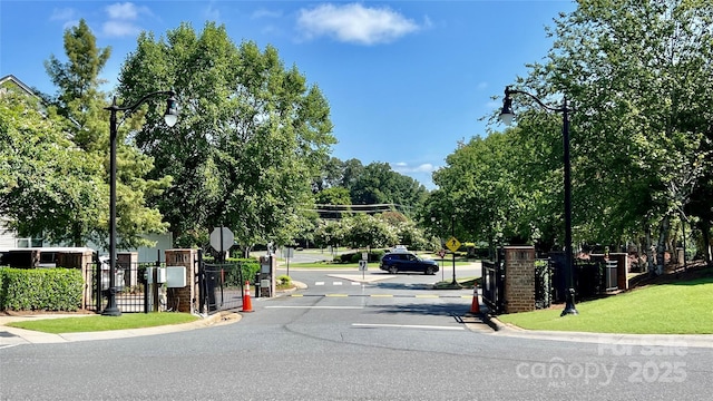 view of street featuring traffic signs, a gated entry, and curbs