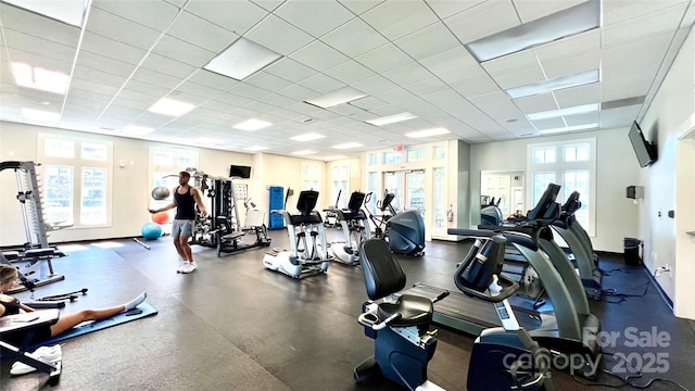 exercise room with a wealth of natural light, a paneled ceiling, and baseboards