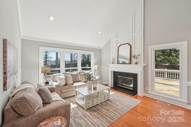 living area featuring a large fireplace, light wood-style flooring, plenty of natural light, and visible vents