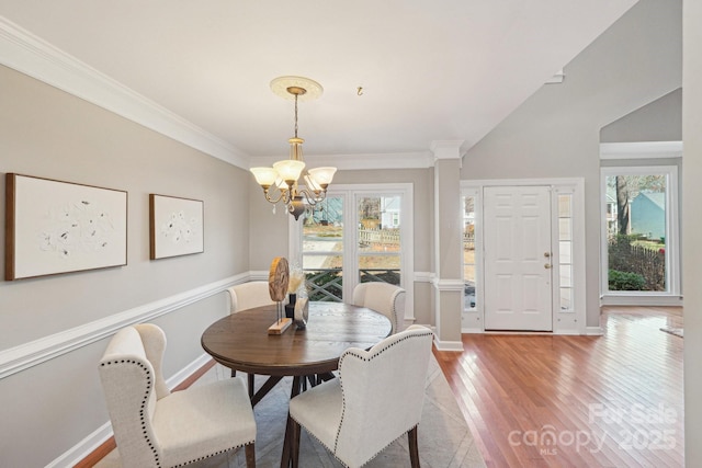 dining area with baseboards, ornamental molding, wood finished floors, and an inviting chandelier