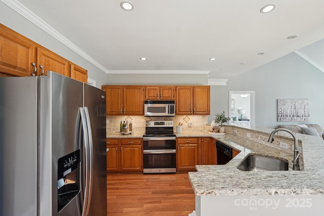 kitchen featuring tasteful backsplash, light wood-style flooring, appliances with stainless steel finishes, a sink, and a peninsula