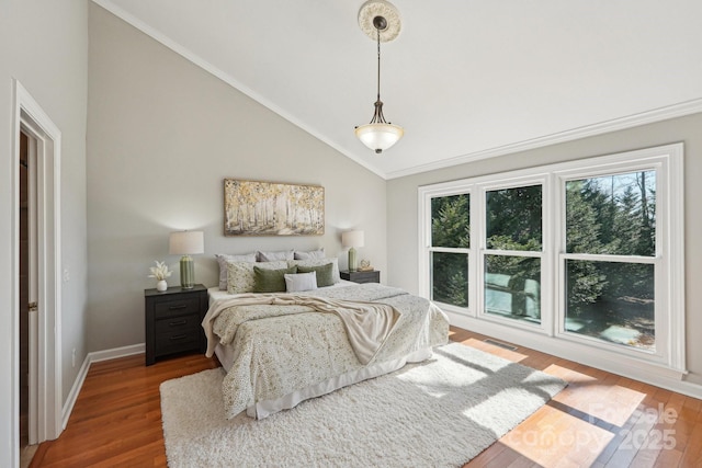 bedroom with high vaulted ceiling, wood finished floors, visible vents, and baseboards