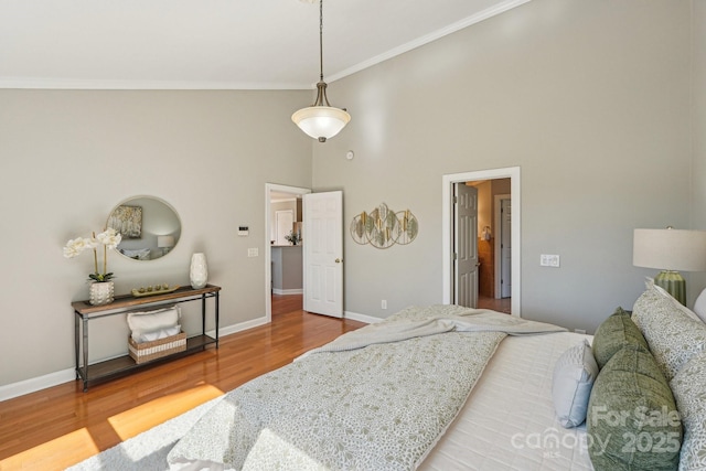 bedroom featuring a high ceiling, wood finished floors, and baseboards